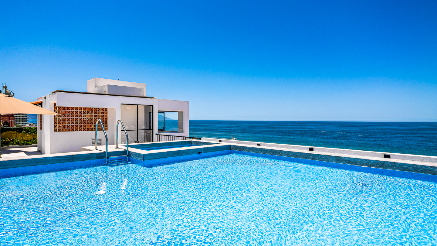Rooftop swimming pool and hot tub overlooking Puerto Vallarta at dusk